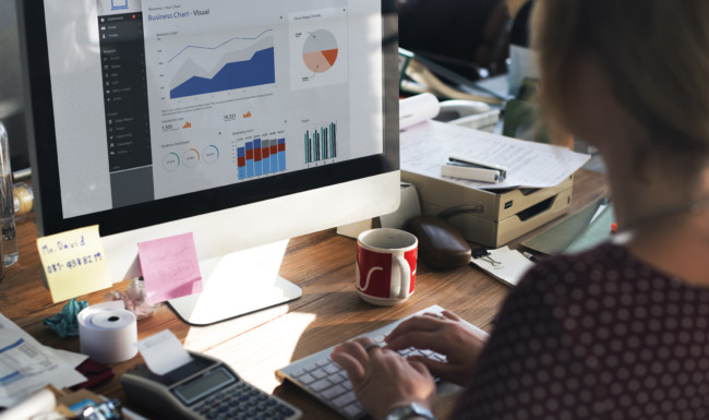 Operator sits in front of computer looking at statistics and graphs of sales data.