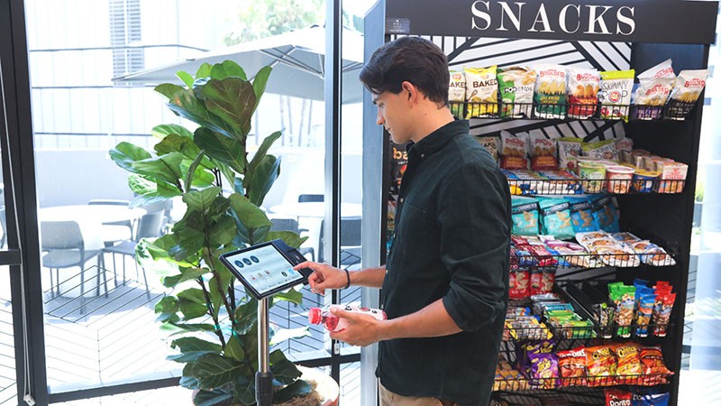 Young man pays at a micro market kiosk.