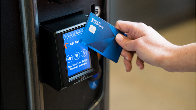 Woman presents card reader to tap for payment at an Engage card reader.