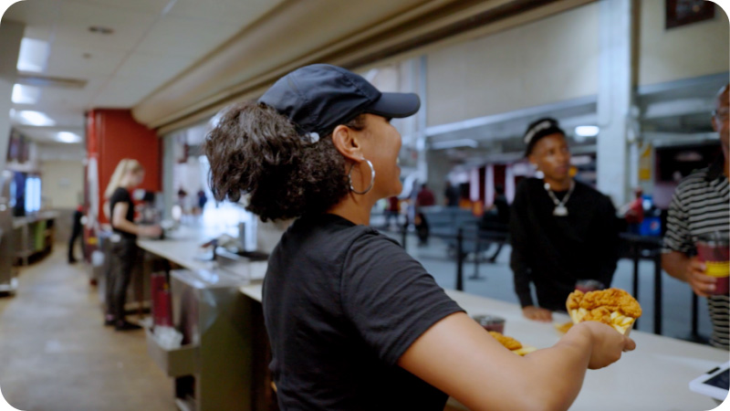 Concessions employee hands food to a customer.