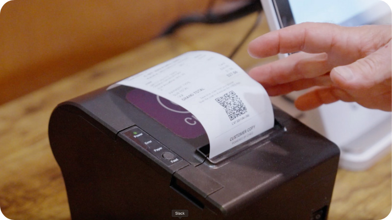 Hand reaches out to receipt printer to give customer a receipt.