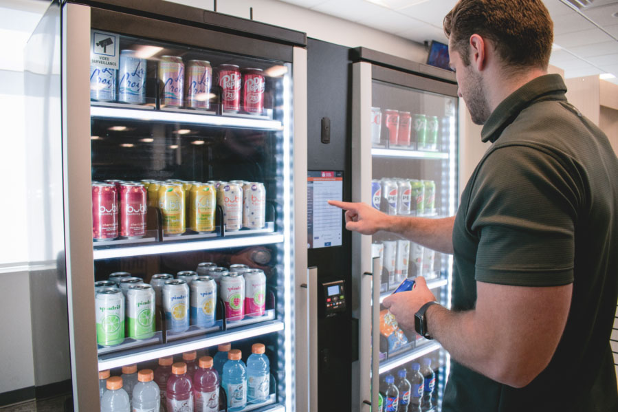 Man stands in front of a Smart Store to restock soda products.