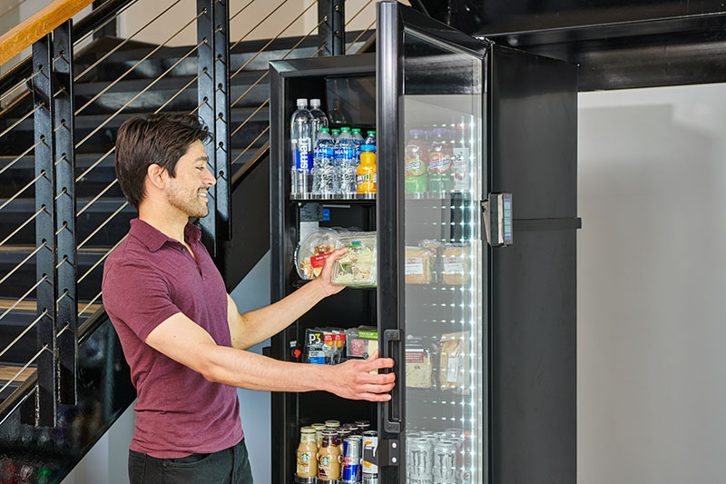 Man pulls a fresh salad out of a Cooler Cafe.