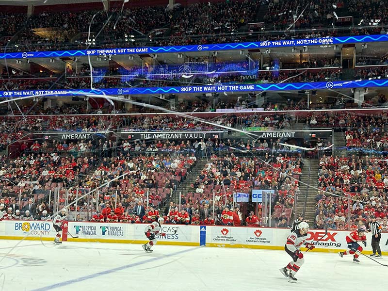 Pro ice hockey stadium filled with fans with Cheq branding on the electronic ribbons.