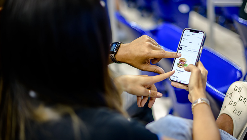 Woman orders food from her phone at a ball game.