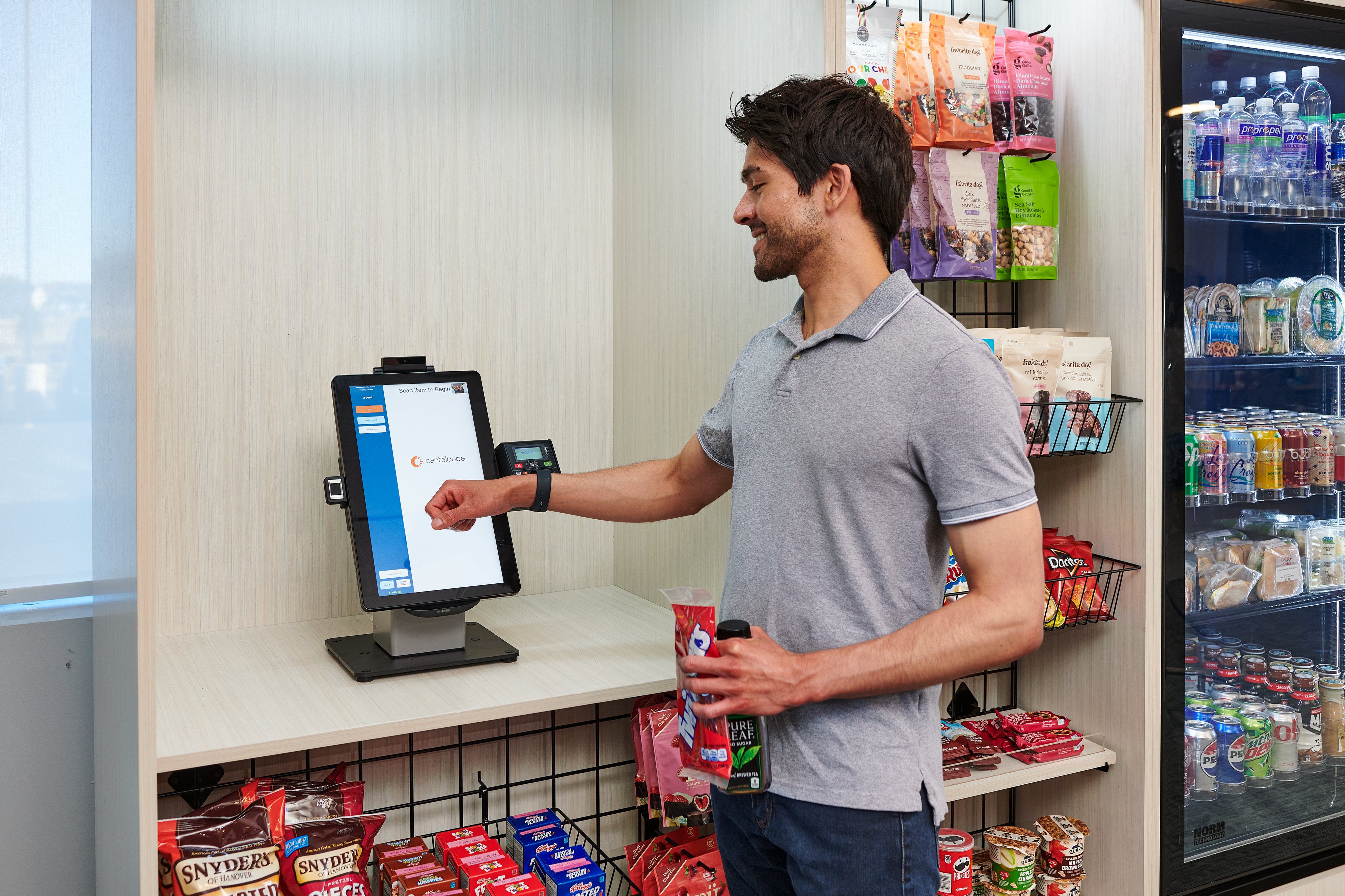 Young man purchases snacks at a micro market kiosk with his smart watch.