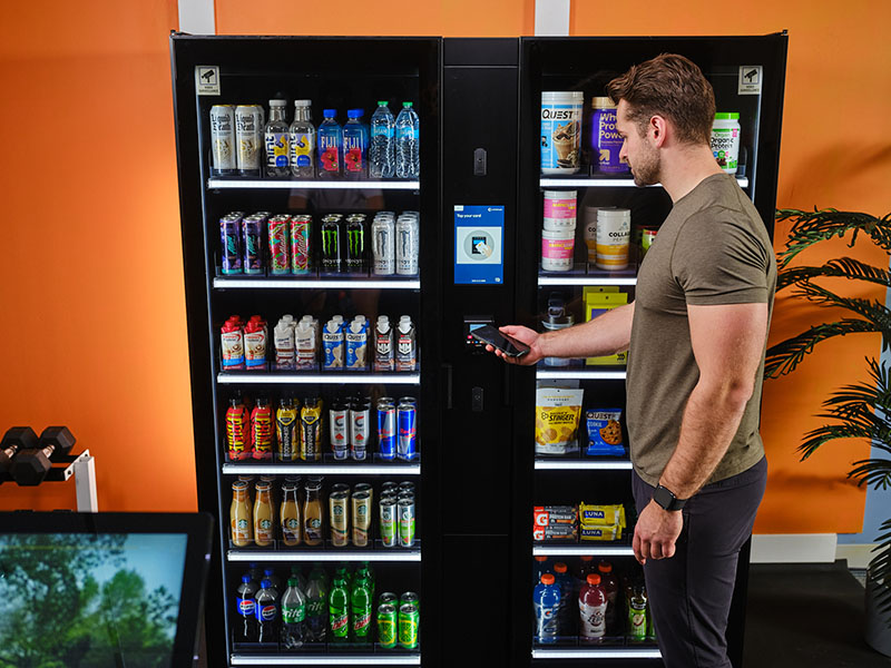 A young man pays for goods at a Smart Store in a fitness center.