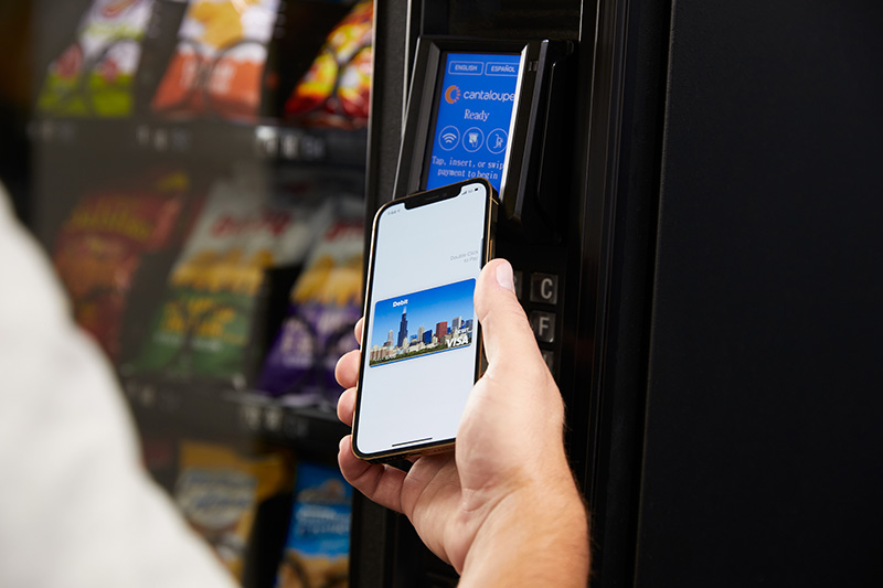 A woman taps her phone to pay at an Engage device.