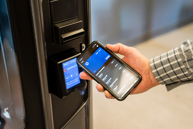 A man uses his phone to tap to pay at a vending machine.
