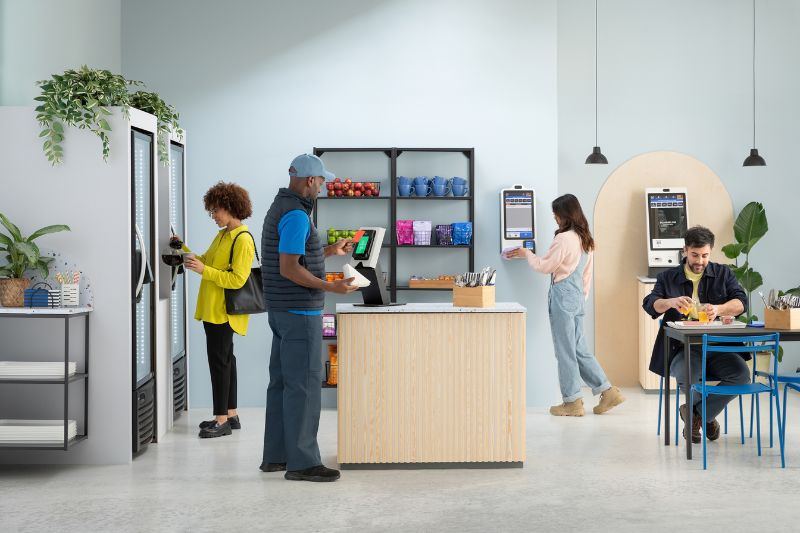 Customers browse a micro market with several kiosk check out options.